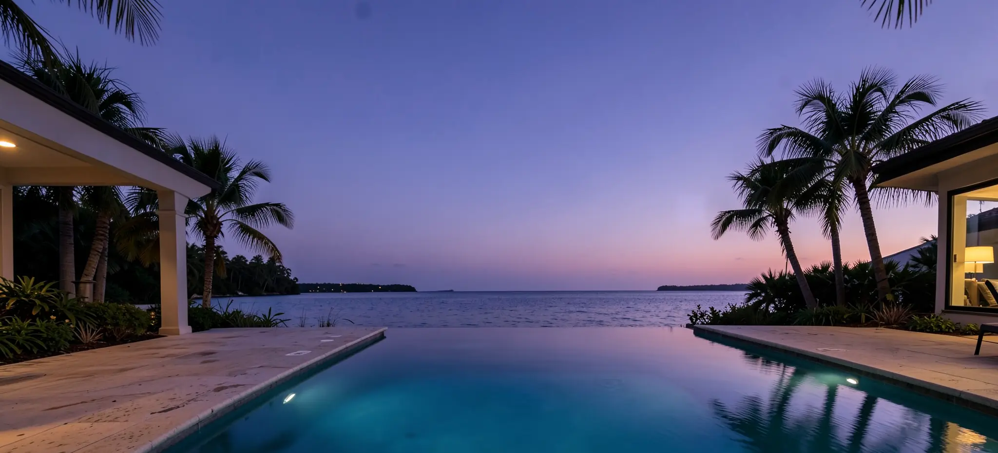 A long infinity-edge pool glowing lagoon blue at dusk beside a limestone deck, palms against a violet sky (illustrative, generated).